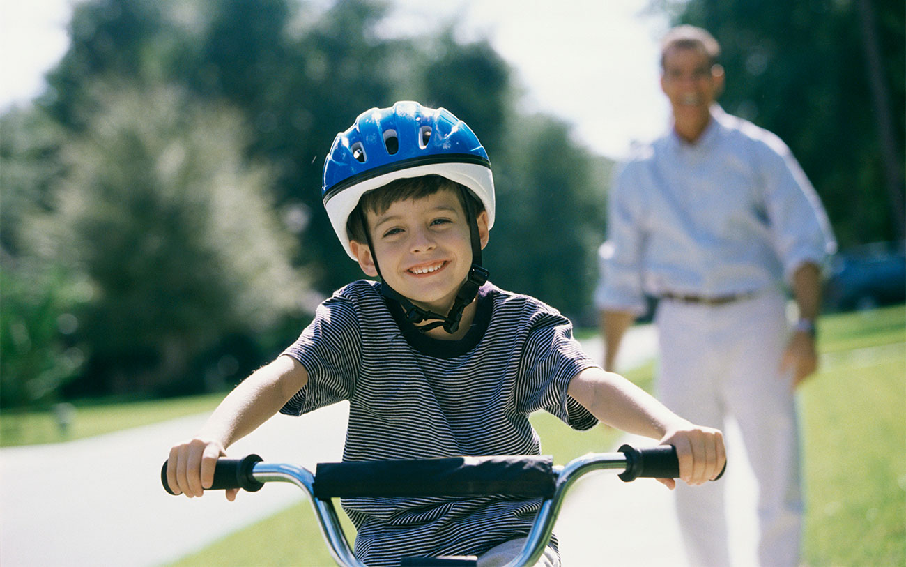father-and-boy-riding-bikes-outdoors-in-new-community